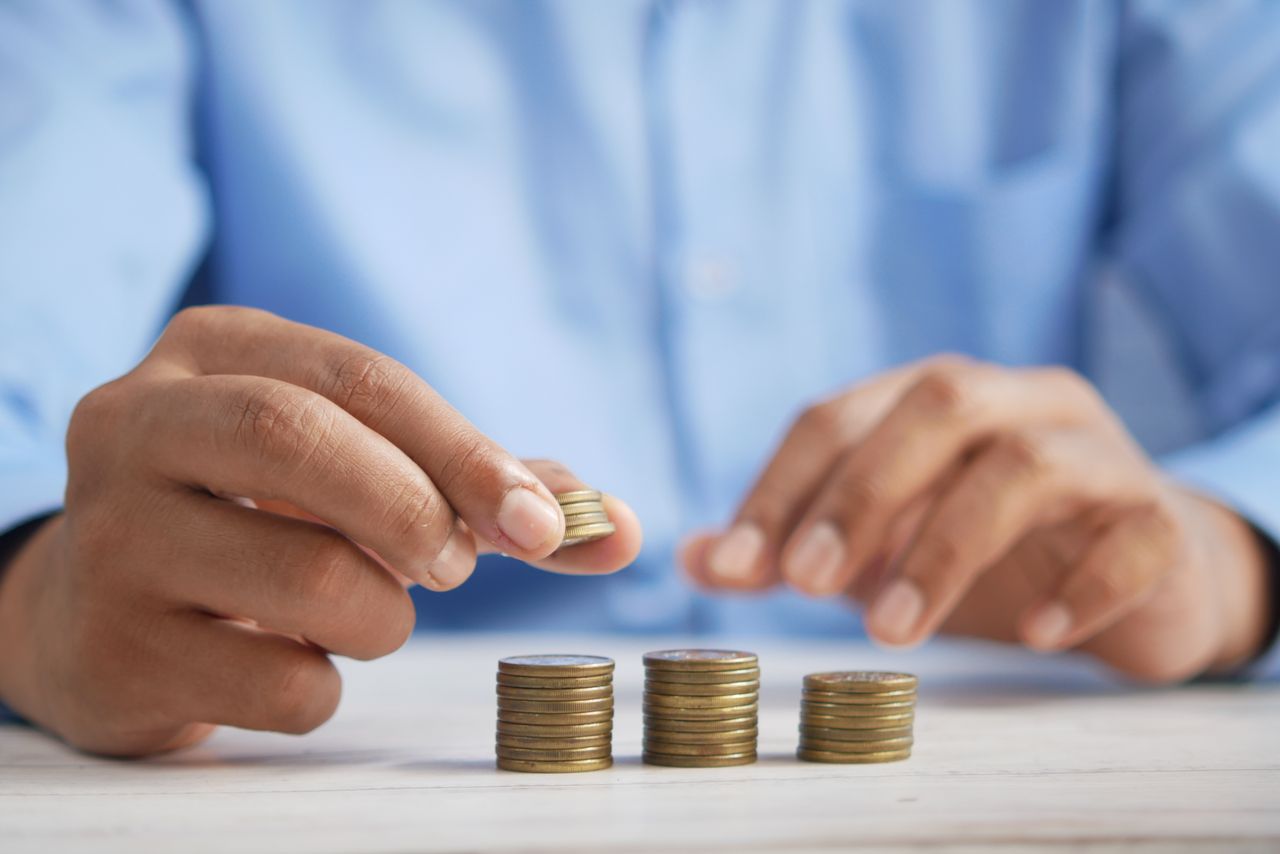 about-us-img Close-up of hands stacking gold coins, symbolizing financial growth and savings.